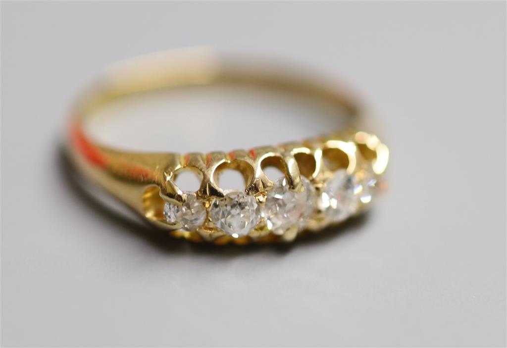 An early 20th century 18ct gold and graduated five stone diamond set half hoop ring, size P, gross 4 grams.